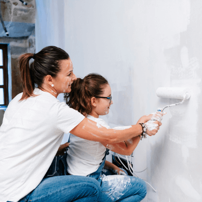 Mother and daughter painting a wall of their house together